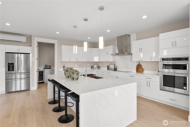 kitchen featuring an AC wall unit, a sink, wine cooler, appliances with stainless steel finishes, and wall chimney range hood