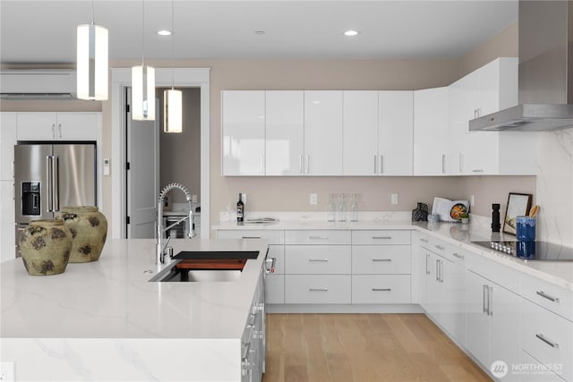 kitchen featuring a wall mounted AC, a sink, high end refrigerator, black electric stovetop, and wall chimney exhaust hood