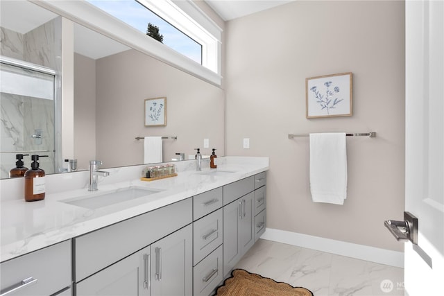 full bathroom with baseboards, marble finish floor, a marble finish shower, and a sink