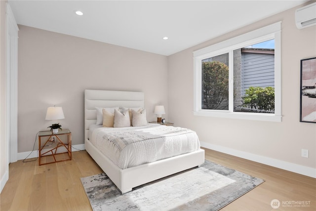 bedroom featuring recessed lighting, baseboards, light wood-style flooring, and a wall unit AC