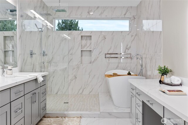 full bathroom with a freestanding tub, a marble finish shower, and vanity