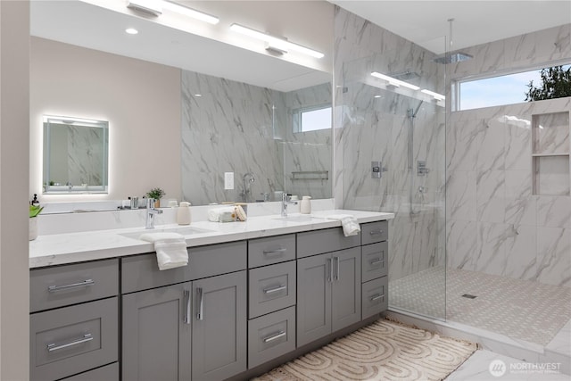 full bath featuring a sink, a marble finish shower, and double vanity