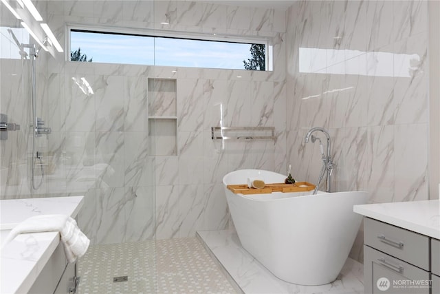 bathroom with a marble finish shower, vanity, and a freestanding tub