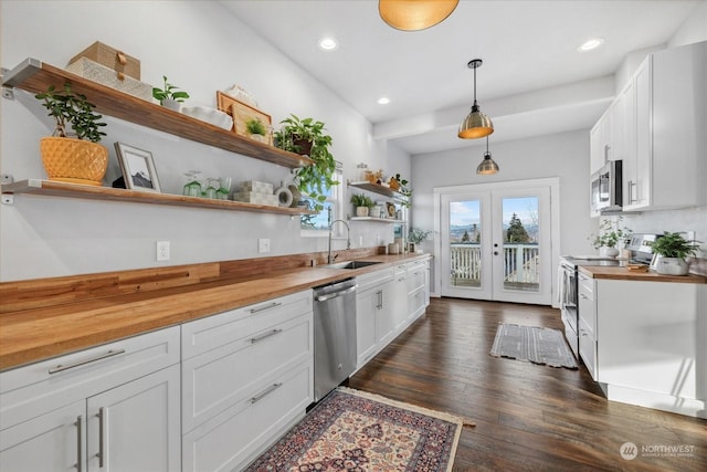 kitchen featuring pendant lighting, white cabinets, stainless steel appliances, sink, and butcher block countertops