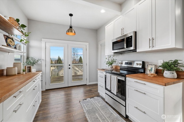 kitchen featuring white cabinets, wood counters, appliances with stainless steel finishes, and pendant lighting