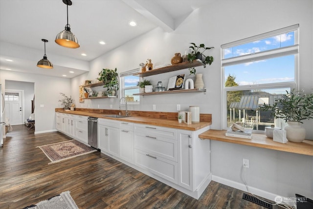 kitchen featuring wood counters, white cabinetry, dark wood-type flooring, hanging light fixtures, and sink