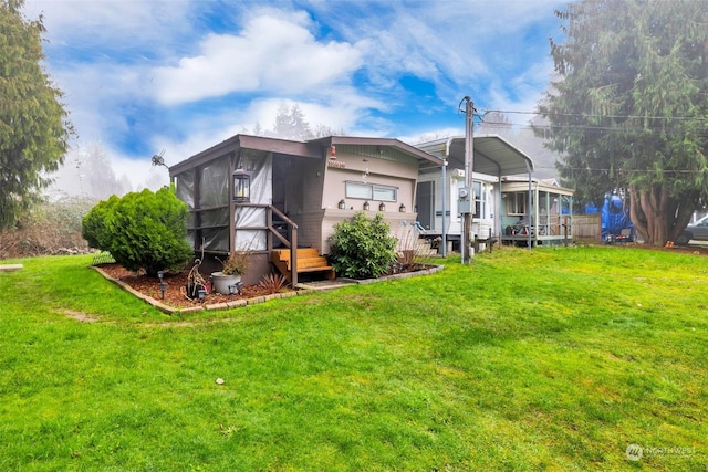 rear view of house featuring a lawn and a carport