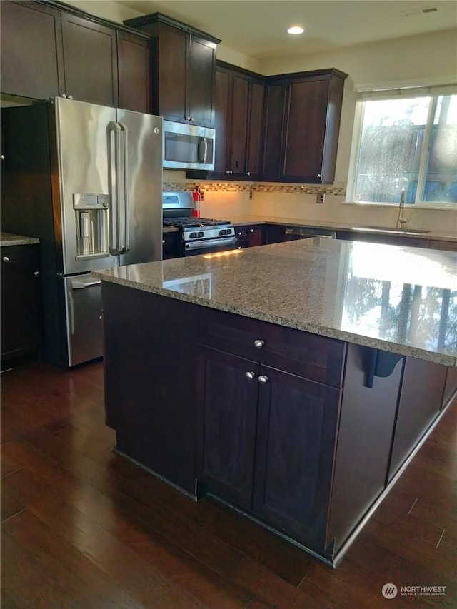 kitchen with light stone counters, sink, dark brown cabinetry, and appliances with stainless steel finishes