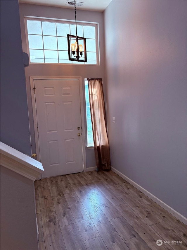 entrance foyer with an inviting chandelier, light hardwood / wood-style flooring, and a high ceiling