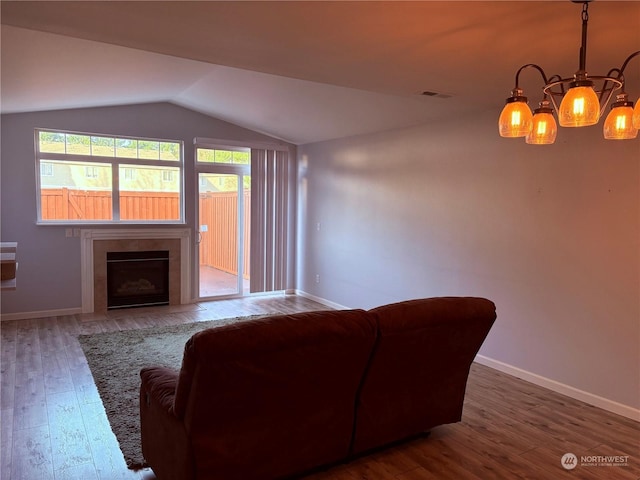 living room with hardwood / wood-style flooring, an inviting chandelier, and vaulted ceiling