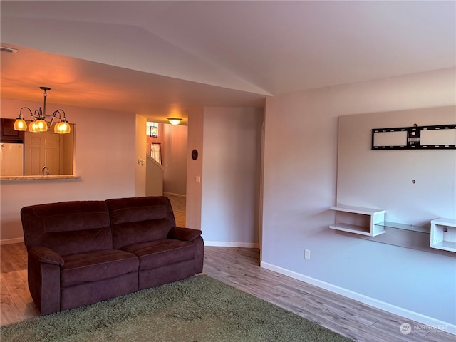 unfurnished living room with hardwood / wood-style flooring, a chandelier, and vaulted ceiling