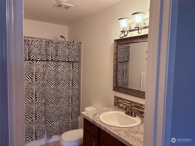 bathroom featuring tile patterned flooring, vanity, backsplash, toilet, and walk in shower