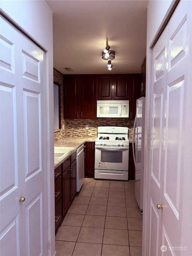 kitchen featuring white appliances, sink, backsplash, light tile patterned flooring, and dark brown cabinets