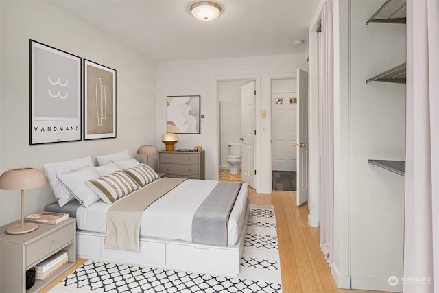 bedroom featuring connected bathroom and light hardwood / wood-style floors