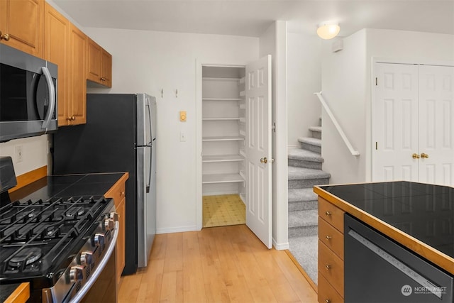 kitchen with light hardwood / wood-style flooring, stainless steel appliances, and tile countertops