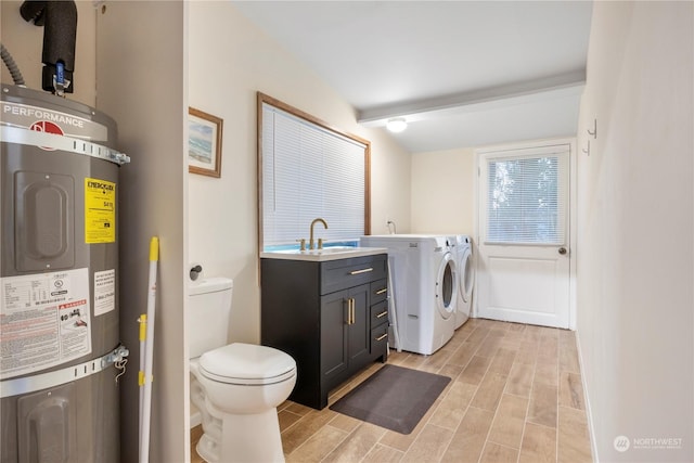 washroom featuring sink, water heater, and separate washer and dryer