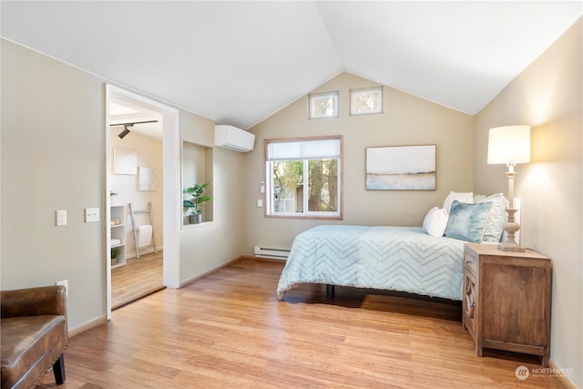 bedroom with ensuite bathroom, lofted ceiling, light hardwood / wood-style floors, a baseboard heating unit, and a wall unit AC