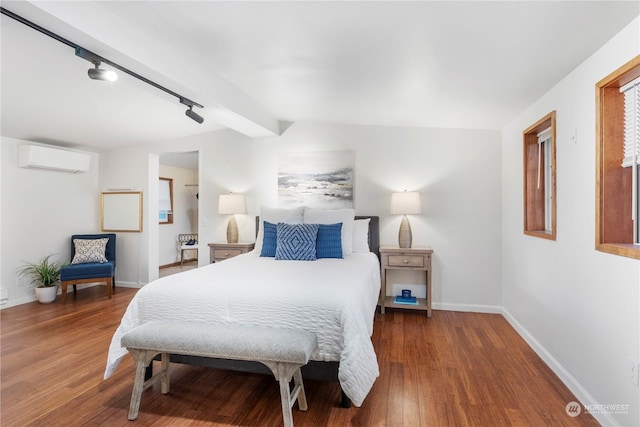 bedroom with wood-type flooring, rail lighting, vaulted ceiling with beams, and a wall mounted AC