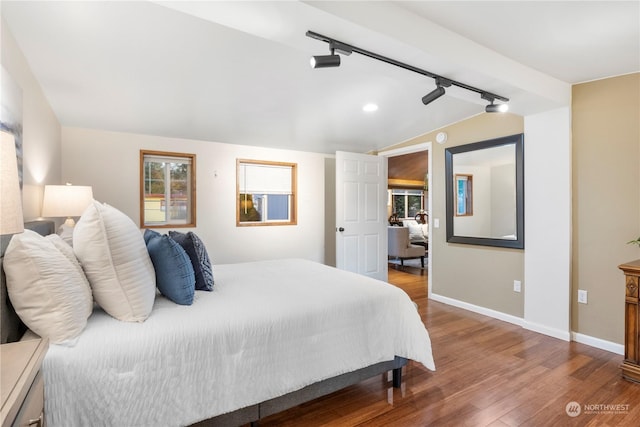 bedroom featuring vaulted ceiling, hardwood / wood-style flooring, and rail lighting