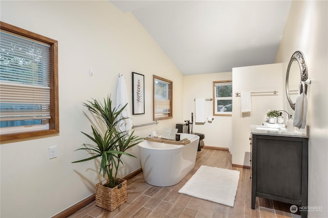 bathroom with vanity, vaulted ceiling, and a bath