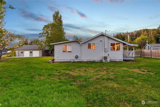 back house at dusk with ac unit, a yard, and an outdoor structure