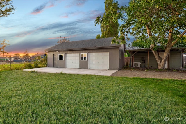 back house at dusk with ac unit, a yard, a garage, and an outdoor structure