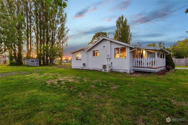 back house at dusk with ac unit and a yard