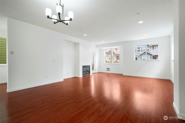 unfurnished living room featuring a chandelier and wood-type flooring