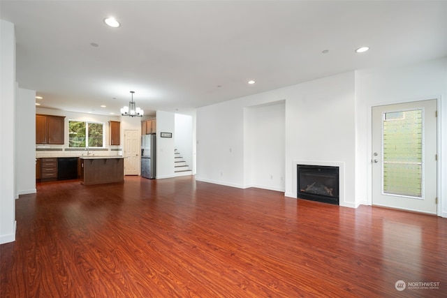 unfurnished living room featuring a chandelier, dark hardwood / wood-style flooring, and sink