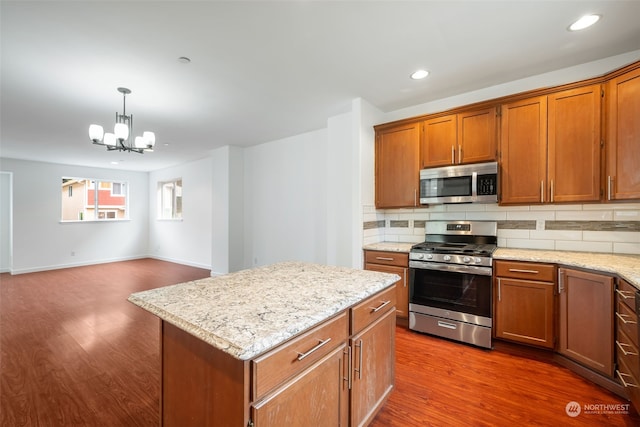 kitchen featuring stainless steel appliances, decorative light fixtures, a center island, tasteful backsplash, and a chandelier