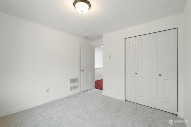 unfurnished bedroom with a closet and light carpet