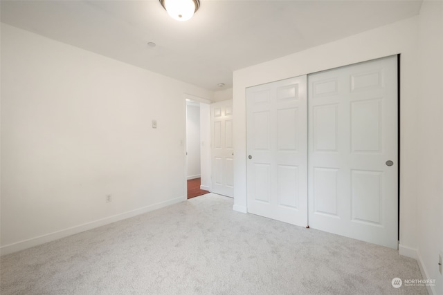 unfurnished bedroom with light colored carpet and a closet