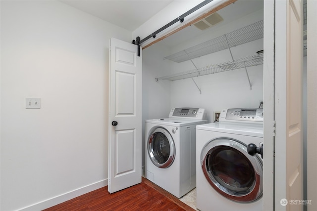 washroom featuring dark hardwood / wood-style floors, a barn door, and independent washer and dryer