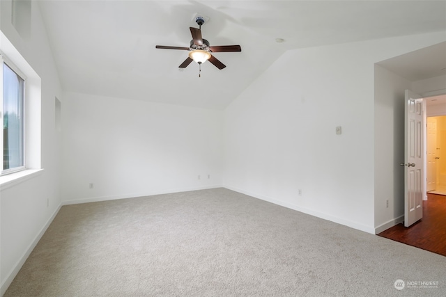 spare room featuring ceiling fan, vaulted ceiling, and dark colored carpet