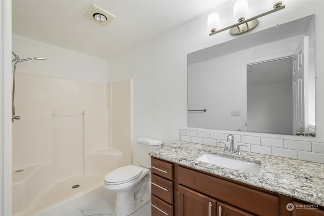 bathroom featuring toilet, a shower, vanity, and decorative backsplash