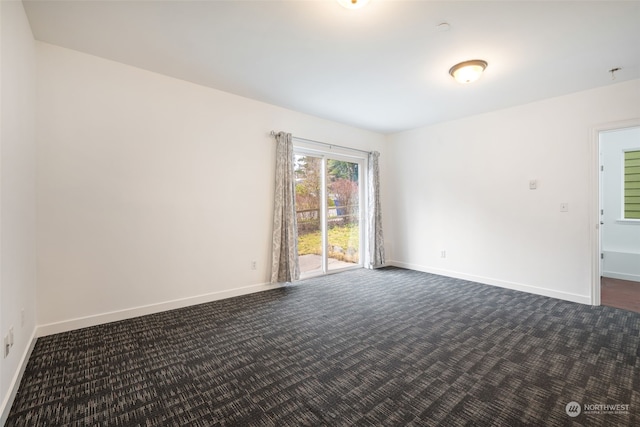 spare room featuring dark colored carpet