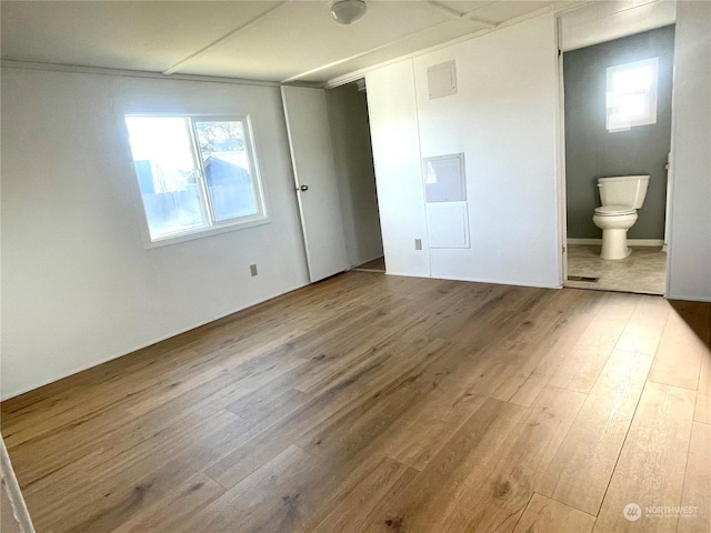 unfurnished bedroom with connected bathroom and hardwood / wood-style flooring