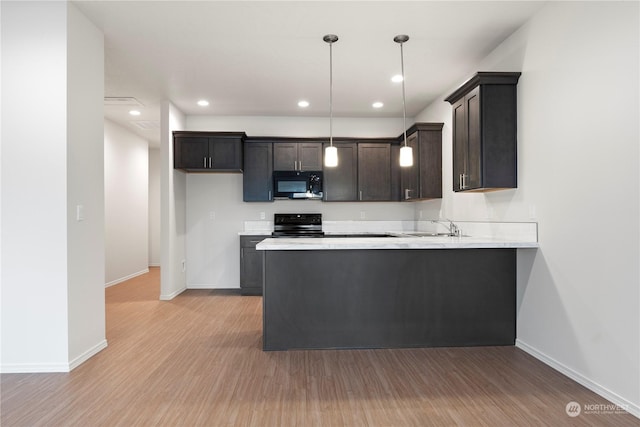 kitchen with black appliances, kitchen peninsula, decorative light fixtures, and light hardwood / wood-style flooring