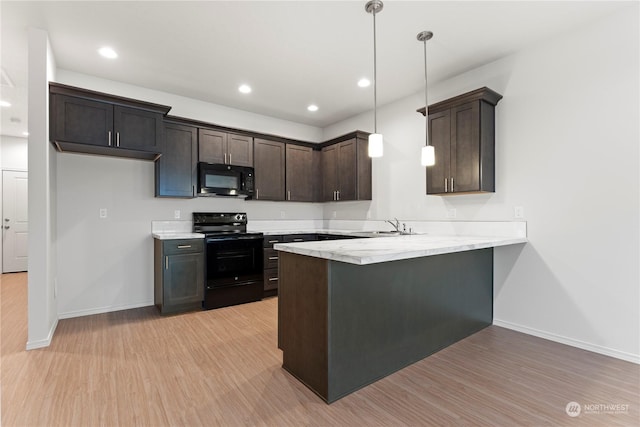 kitchen featuring pendant lighting, black appliances, kitchen peninsula, light wood-type flooring, and dark brown cabinets