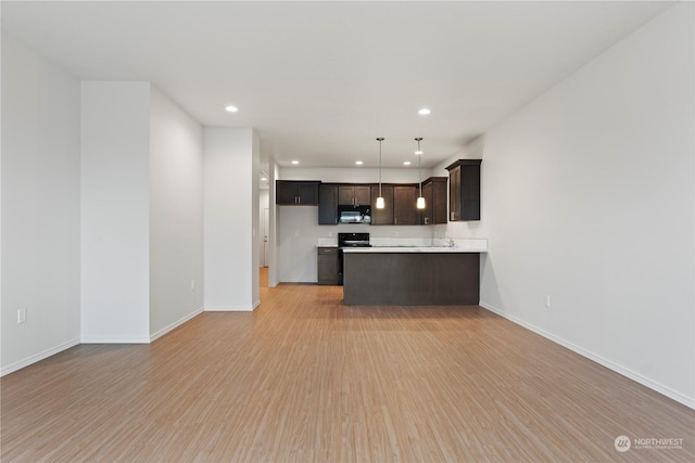 kitchen with light wood-type flooring, dark brown cabinetry, range, and hanging light fixtures