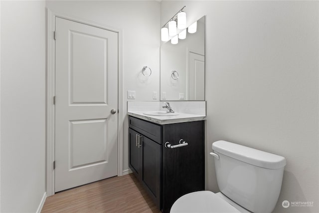 bathroom with toilet, hardwood / wood-style floors, and vanity