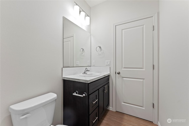 bathroom with toilet, hardwood / wood-style floors, and vanity