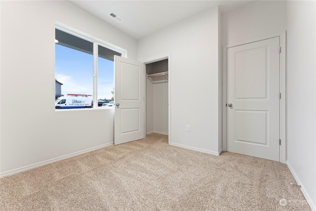 unfurnished bedroom with light colored carpet and a closet