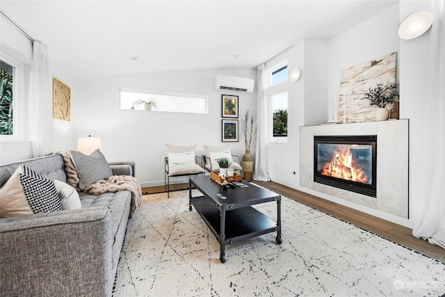 living room with lofted ceiling, an AC wall unit, a wealth of natural light, and light hardwood / wood-style flooring