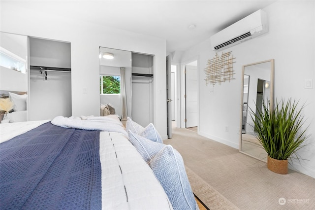 bedroom with an AC wall unit, two closets, and light carpet