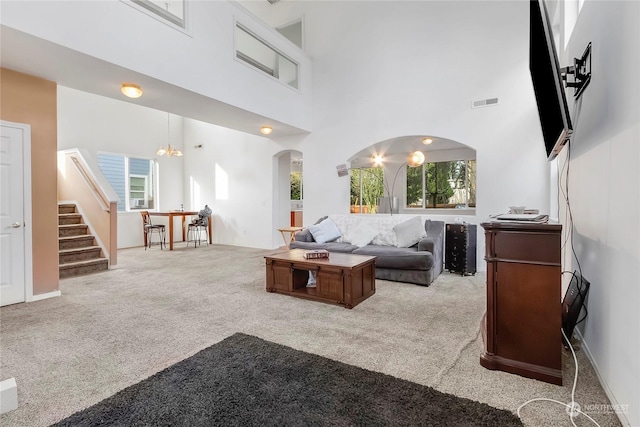 carpeted living room featuring a notable chandelier and a high ceiling