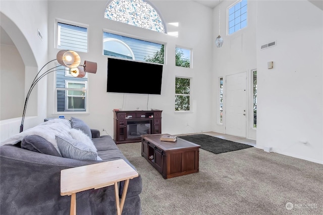 carpeted living room featuring a towering ceiling