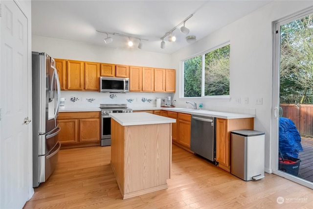 kitchen featuring a kitchen island, light wood-type flooring, sink, and appliances with stainless steel finishes