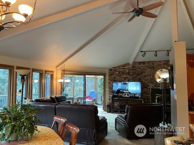 living room with ceiling fan with notable chandelier and lofted ceiling with beams