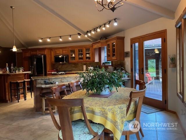 tiled dining space featuring beamed ceiling and a chandelier